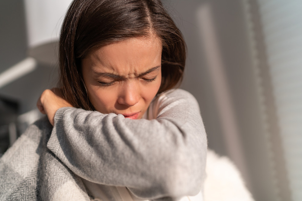 woman sneezing into arm