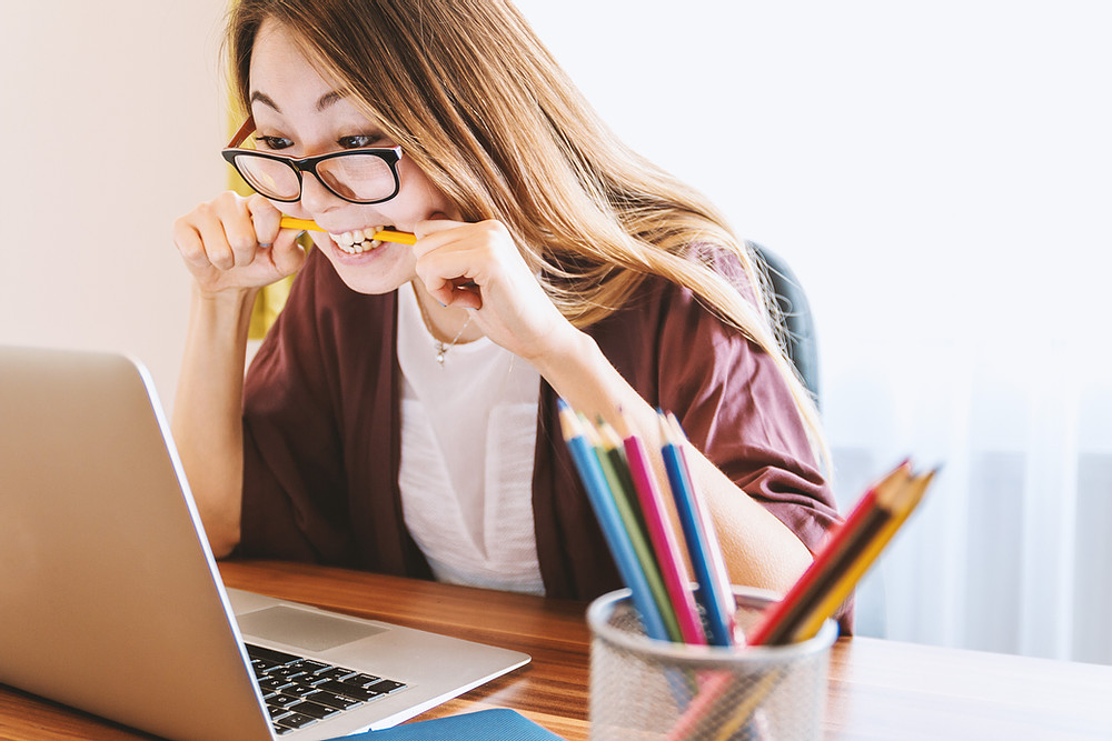 woman stressed and chewing on a pencil in front of computer